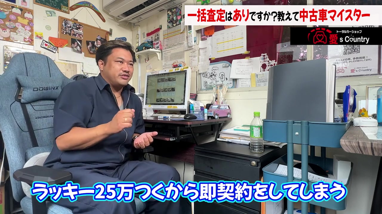 デスクで一括査定について解説する中古車販売店の社長