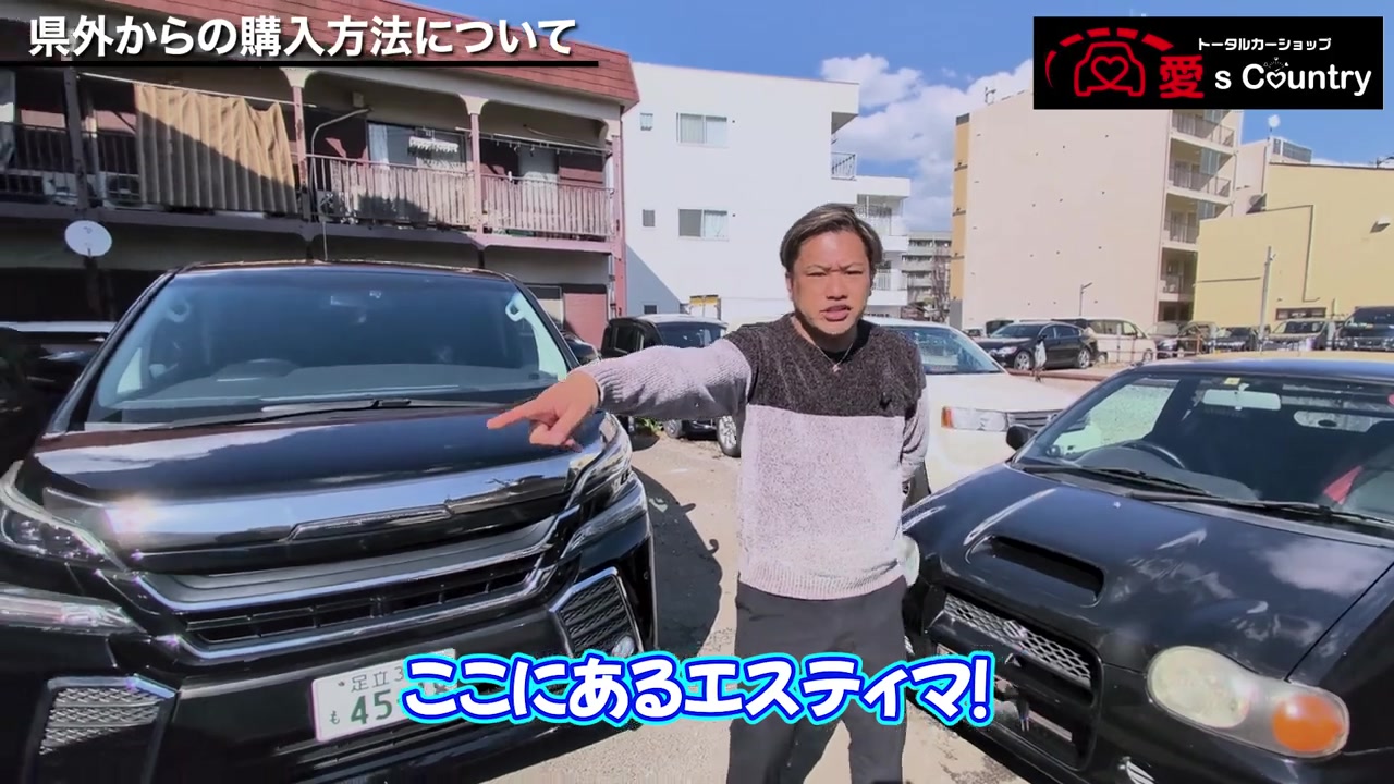 店頭の在庫車を指しながら県外納車について語る社長