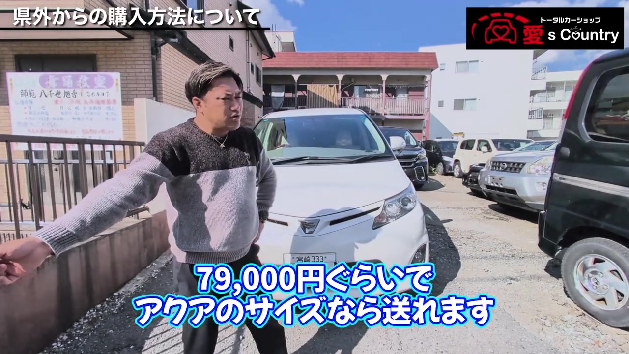 宮崎ナンバーの白い車を前に沖縄への輸送費を説明する社長