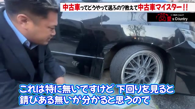 車の下回りをしゃがんで覗き込み錆を確認する国岡社長
